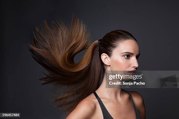 studio shot of young woman tossing hair - ponytail hair stock pictures, royalty-free photos & images