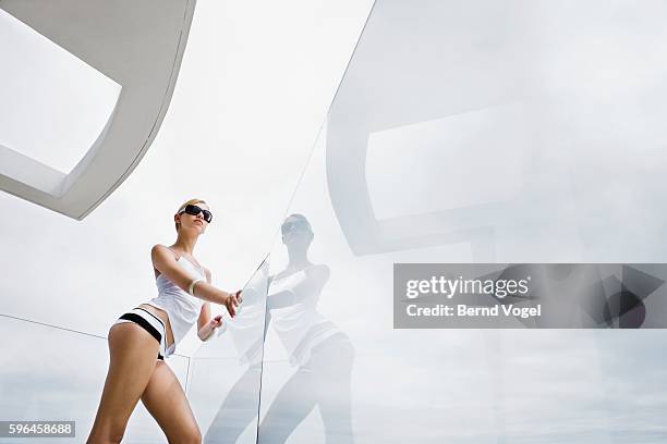 woman posing against glass balcony - junge frau allein stock-fotos und bilder