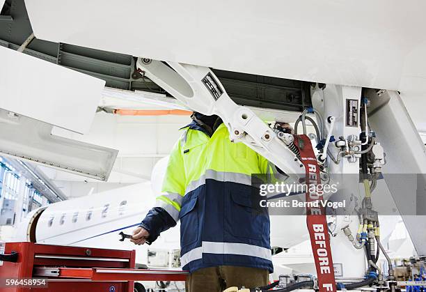 aviation mechanic making repairs to jet plane - landing gear - fotografias e filmes do acervo