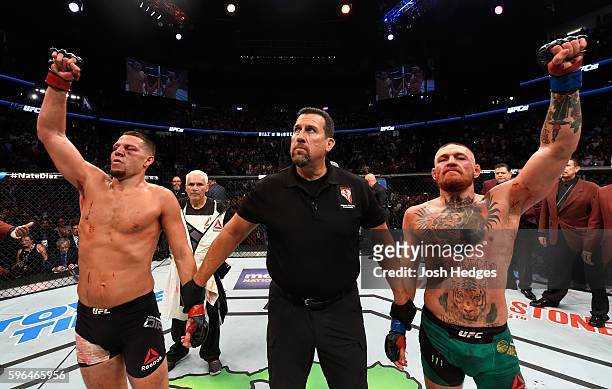 Conor McGregor of Ireland and Nate Diaz raise their hands and wait to hear the judges decision after their welterweight bout during the UFC 202 event...
