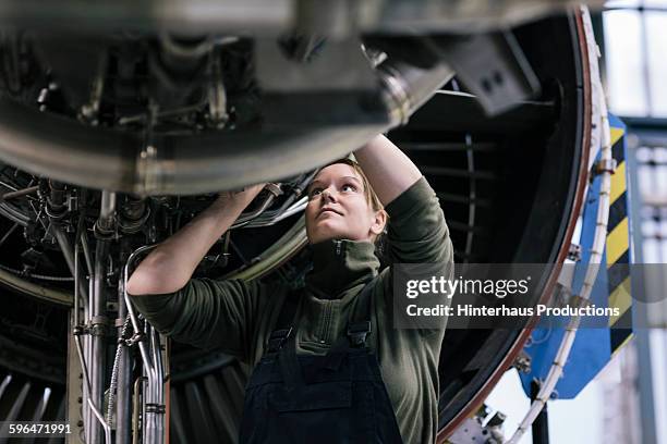 female engineer working on jet engine - repairman photos et images de collection