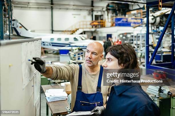 two aircraft engineers in hangar - flugzeugmechaniker stock-fotos und bilder