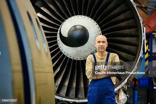 mechanic standing in front of jet engine - motore d'aeroplano foto e immagini stock