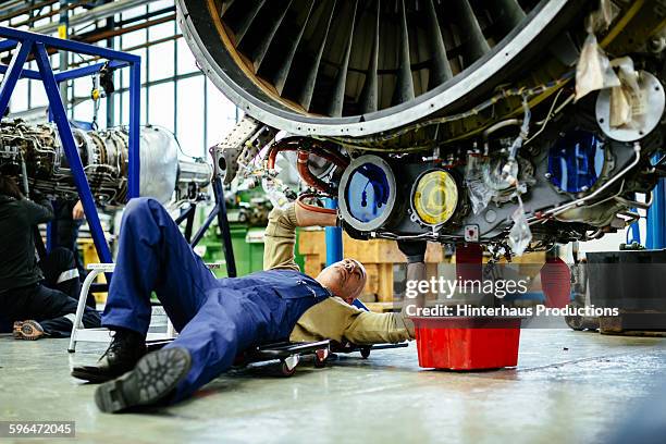 aircraft mechanic lying underneath a jet engine - jet lag stockfoto's en -beelden