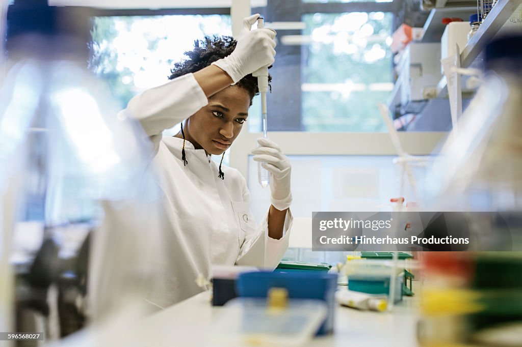 Black female scientist pipetting in a laboratory