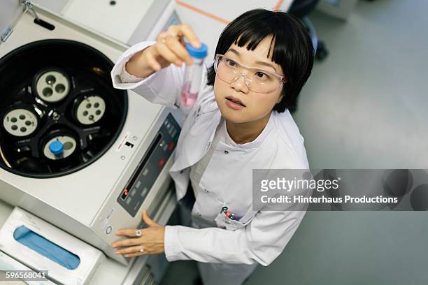 asian scientist taking a look at a flask - mid adult stock-fotos und bilder