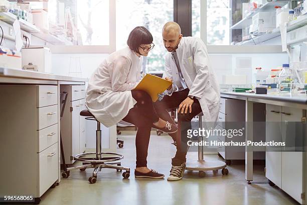 two scientists inside a laboratory discussing - scientist in laboratory imagens e fotografias de stock