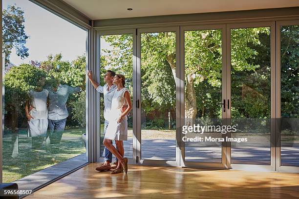 loving couple looking through glass window - raam stockfoto's en -beelden