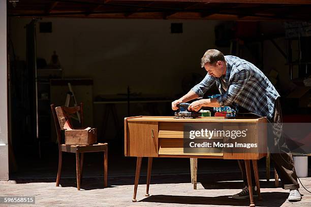 man polishing furniture outside house - carpenter stock pictures, royalty-free photos & images