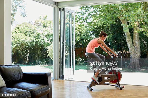 woman working out on exercise bike at home - indoor cycling stock pictures, royalty-free photos & images