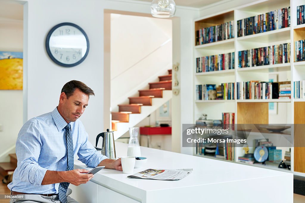 Businessman using mobile phone while having coffee