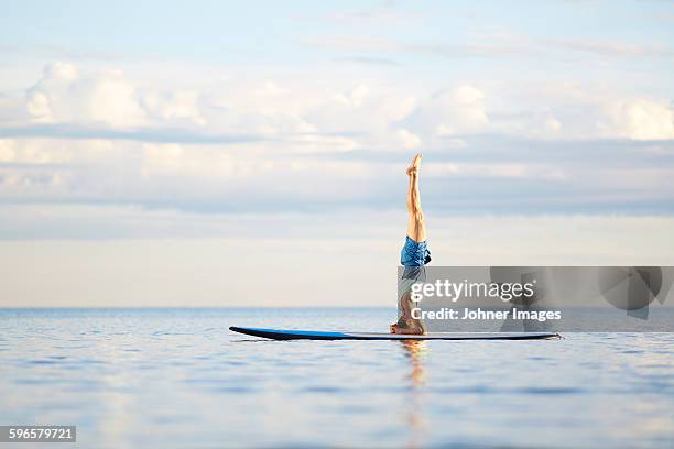 man doing yoga on paddleboard - practioners enjoy serenity of paddleboard yoga stockfoto's en -beelden