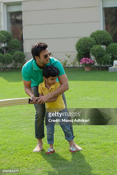 india, father teaching young boy (4-5) to play cricket on backyard - backyard cricket stock pictures, royalty-free photos & images