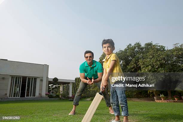 india, young boy (4-5) playing cricket with father on backyard - family cricket stockfoto's en -beelden
