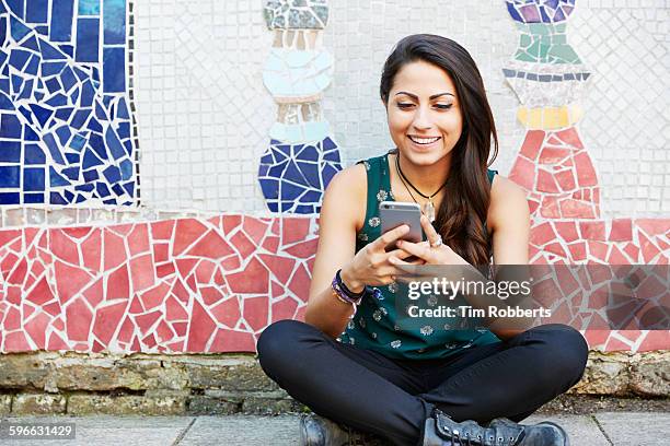 young woman with sat with smartphone, mosaic wall. - streetart stock pictures, royalty-free photos & images