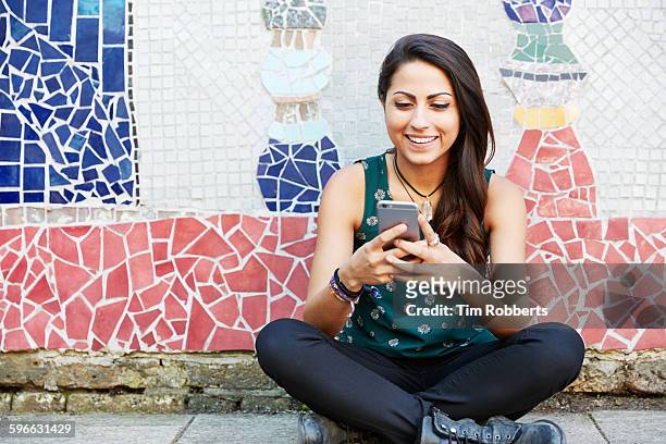young woman with sat with smartphone, mosaic wall. - sattel bildbanksfoton och bilder
