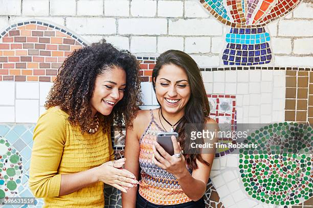 Friends with smartphone in front of mosaic wall