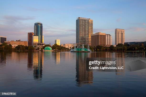 orlando, florida skyline reflecting in lake eola - orlando, florida - orlando florida buildings stock pictures, royalty-free photos & images