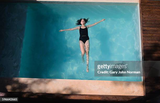 woman floating on her back in pool. - woman pool relax stockfoto's en -beelden