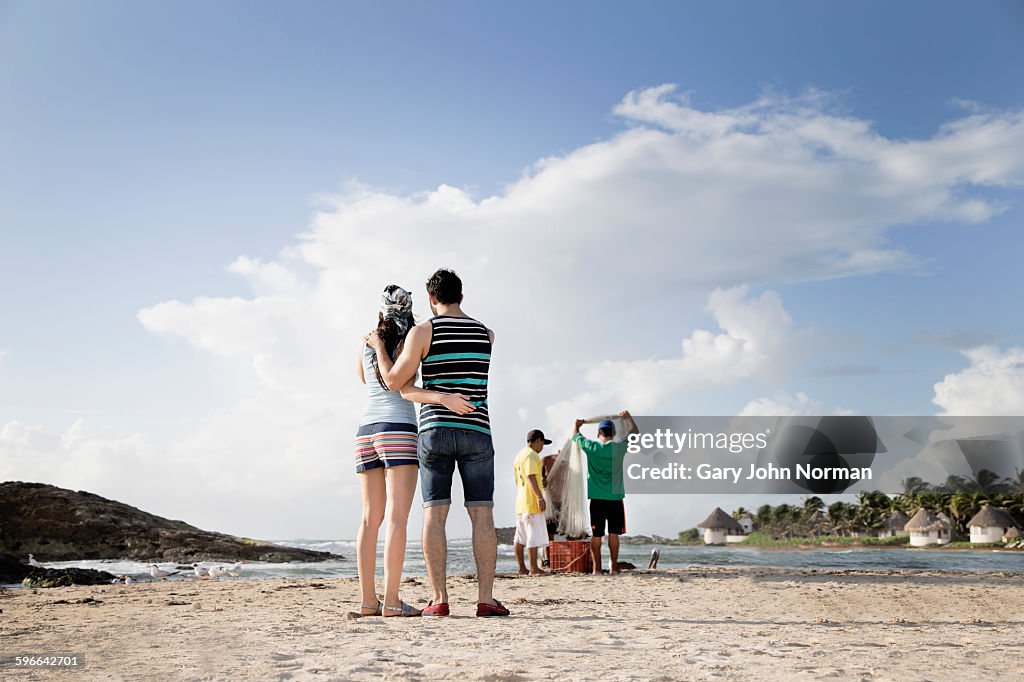 Tourists watching fishermen on beach