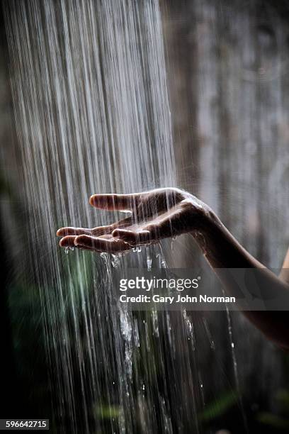woman's hand held under shower water - running water stock-fotos und bilder