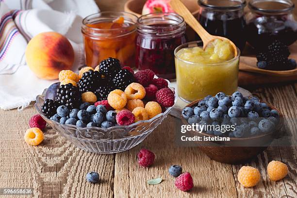 ripe fruits and berries and assorted  of homemade jam  on  rustic wooden table. peach, apple, rasberry, blueberry and blackberry confiture in glass jars - breakfast ingredients stock pictures, royalty-free photos & images