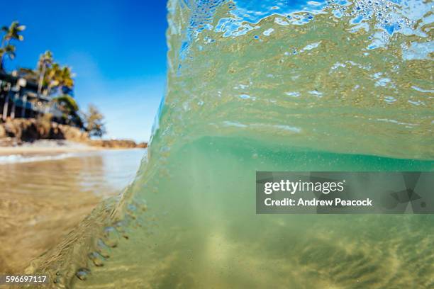 a wave breaks on the shore at little cove beach - noosa beach stock pictures, royalty-free photos & images