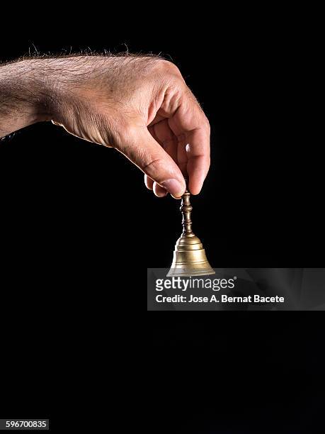 hand holding a bell of bronze on black background - campana de mano fotografías e imágenes de stock