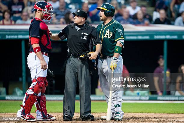 Catcher Chris Gimenez of the Cleveland Indians home plate umpire Tripp Gibson and Billy Butler of the Oakland Athletics have a heated discussion...