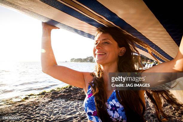 middle age woman prepares to go paddle boarding - beach hold surfboard stock-fotos und bilder