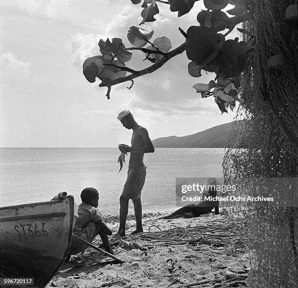 Local fishermen stands on the beach with two friends in Charlotte Amalie, St. Thomas, US Virgin Islands.