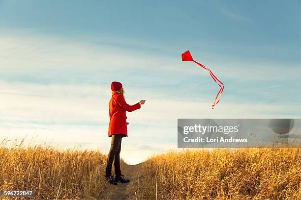 woman in red flying a kite - kite flying stock pictures, royalty-free photos & images