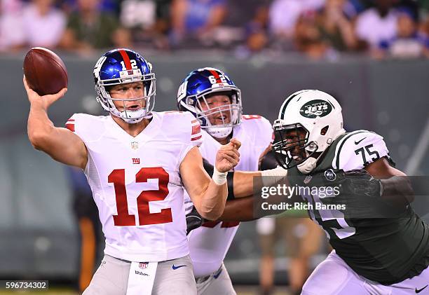 Ryan Nassib of the New York Giants passes the ball as Shelby Harris of the New York Jets defends during the third quarter at MetLife Stadium on...