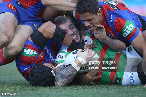 Aaron Gray of the Rabbitohs is tackled by the Knights defence during the round 25 NRL match between the Newcastle Knights and the South Sydney...