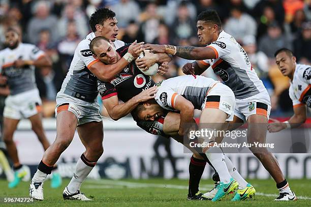 Simon Mannering of the Warriors is tackled by Elijah Taylor and Dene Halatau of the Tigers during the round 25 NRL match between the New Zealand...