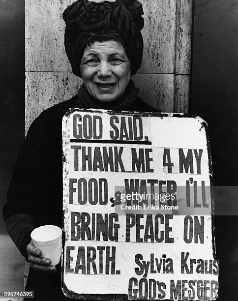 Sylvia Kraus, who claims to be God's Messenger, holds a sign which reads 'God Said: Thank me 4 my food & water I'll bring peace on Earth, New York...