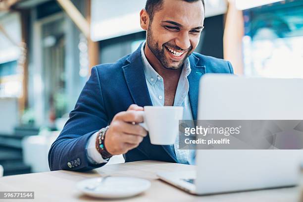 young man making business in the coffee break - arab on computer imagens e fotografias de stock