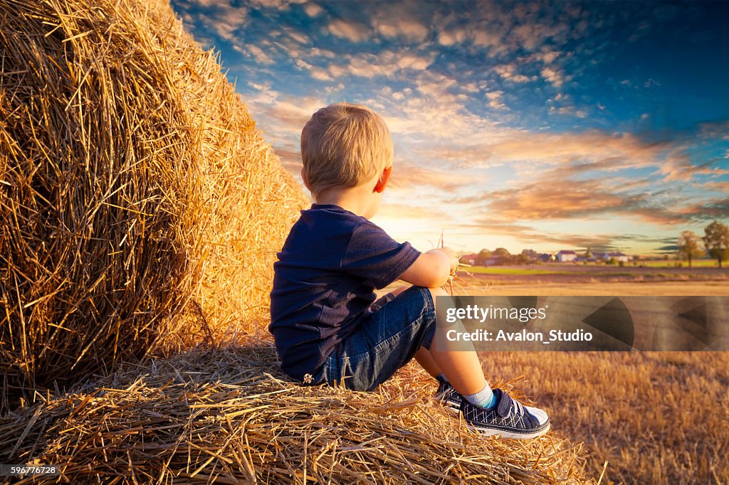 Child sitting on bales of straw