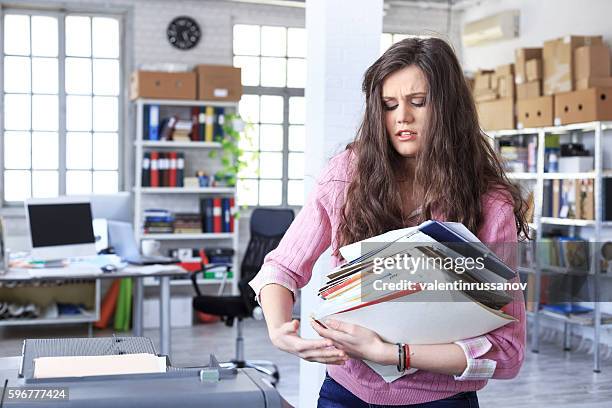 young woman carrying a heavy pile of papers - carrying bildbanksfoton och bilder