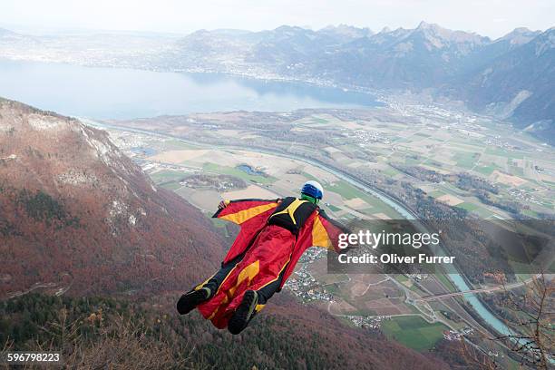 jumper within a wingsuit exited from a cliff - wing suit stock pictures, royalty-free photos & images