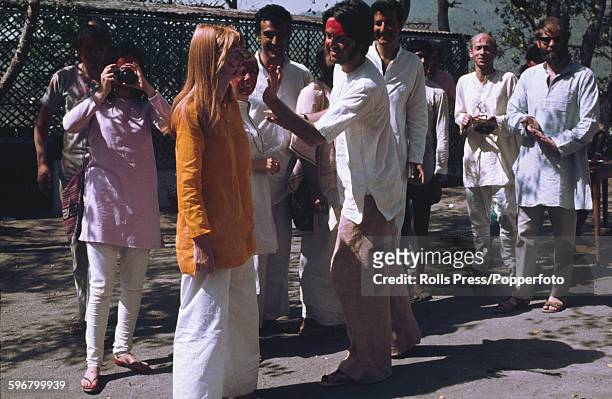 Paul McCartney from The Beatles pictured daubing red paint on the face of his girlfriend Jane Asher during a 'holi' ceremony observed by various...