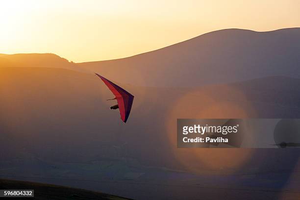 ultralight -hang glider pilot launching,lens flare,castelluccio,apennines,italy - paragliding stockfoto's en -beelden