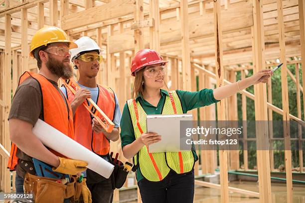 workers at construction job site inside framed building. - blueprint stock pictures, royalty-free photos & images