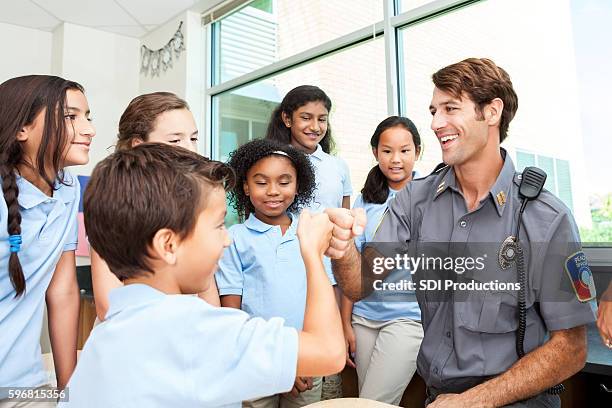 friendly police officer gives fist bump to student - school officer stock pictures, royalty-free photos & images