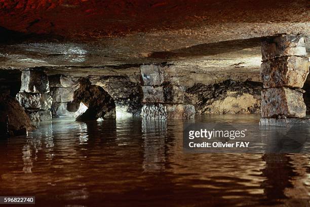 The shadow of a man exploring the watery catacombs of Paris below Rue de l'Aude in the 14th district of Paris, flooded gallery and pillar.