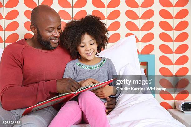 dad reads a book with his daughter - maroon stock pictures, royalty-free photos & images