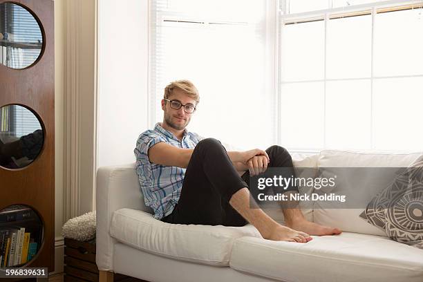 young man relaxing at home - blonde glasses stock-fotos und bilder