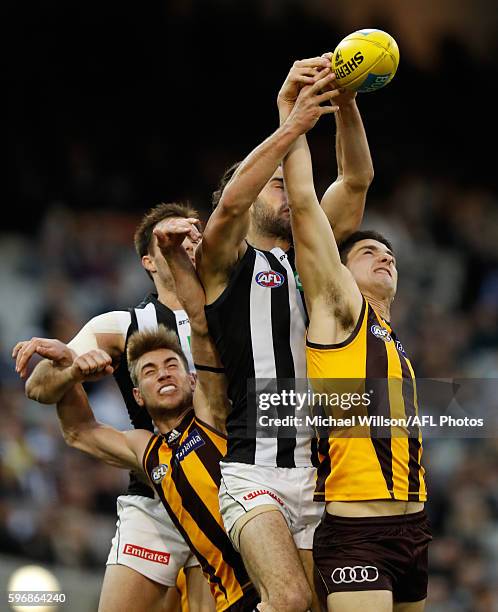 Ryan Schoenmakers of the Hawks, Brodie Grundy of the Magpies and Marc Pittonet of the Hawks compete for the ball during the 2016 AFL Round 23 match...