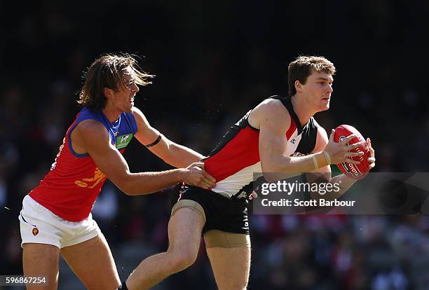 Blake Acres of the Saints is tackled during the round 23 AFL match between the St Kilda Saints and the Brisbane Lions at Etihad Stadium on August 28,...