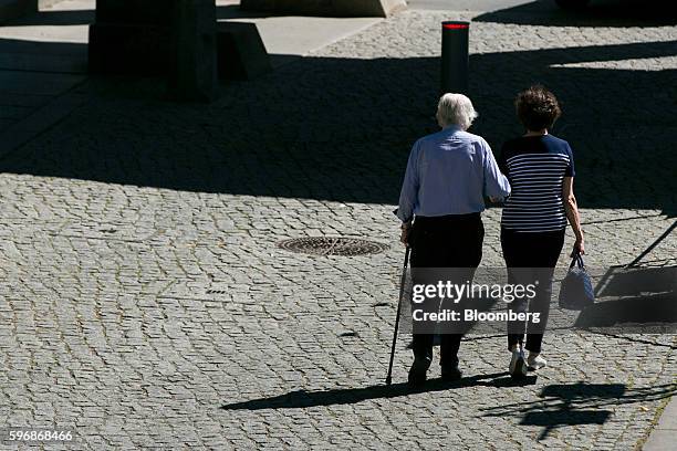 Pensioner, left, walks along a cobbled street with the aid of a walking stick in Berlin, Germany, on Friday, Aug. 26, 2016. Germany's Bundesbank said...